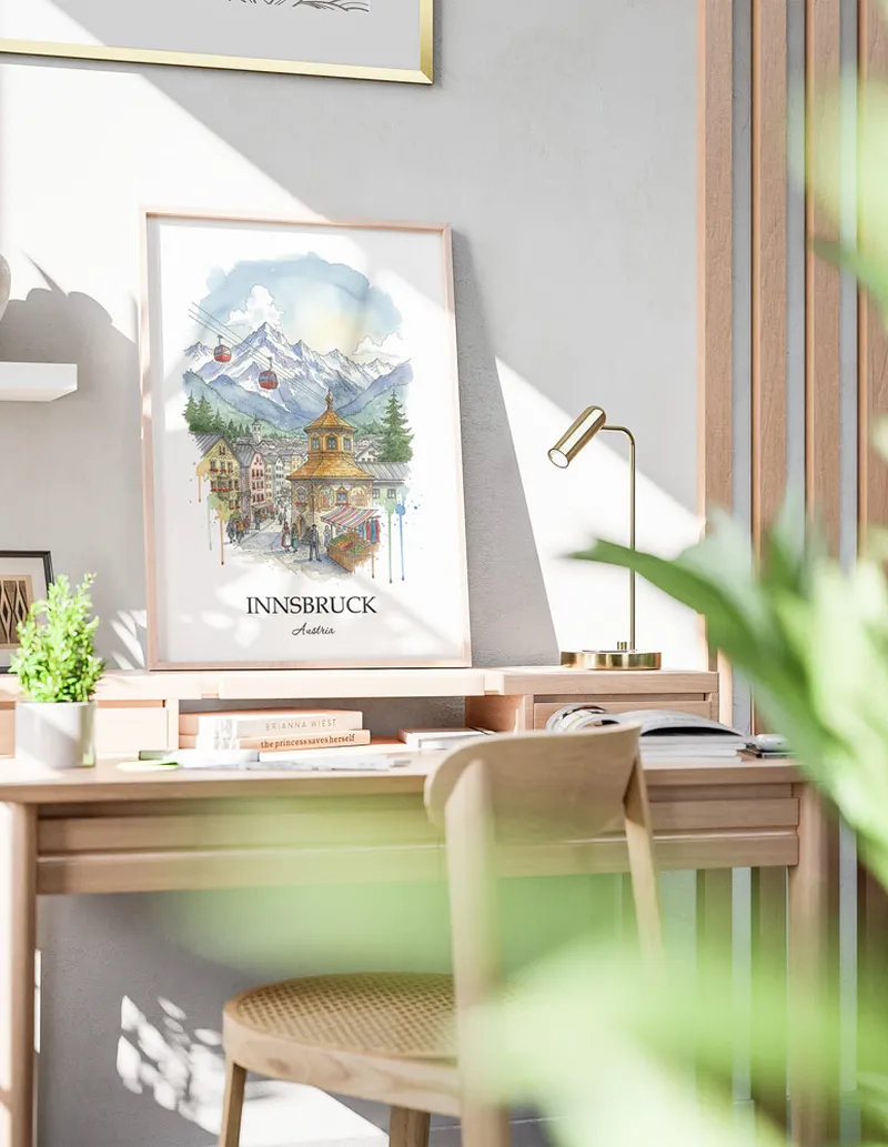 Cozy, well-lit workspace with a minimalist poster of Innsbruck, Austria in a light frame sitting on the desk.