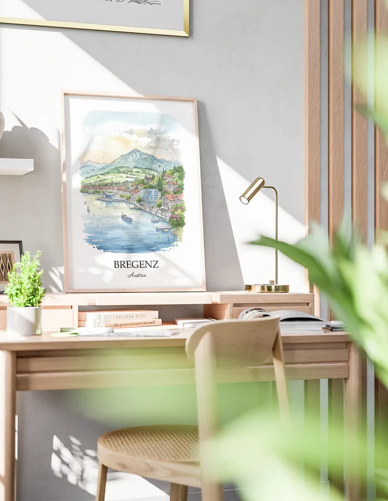 Cozy, well-lit workspace with a minimalist poster of Bregenz, Austria in a light frame sitting on the desk.
