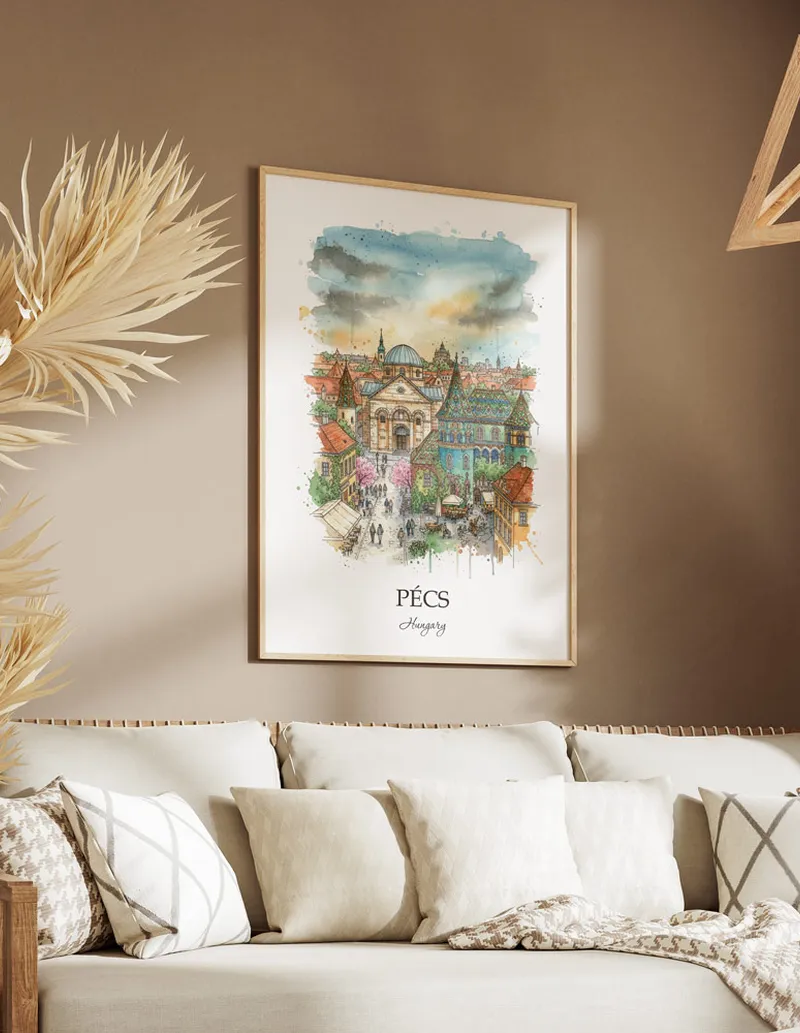 Vintage travel poster of Pécs city, Hungary in a light frame displayed above a sofa in a bright boho interior.