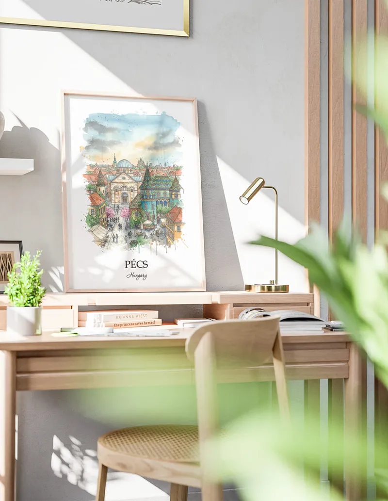 Cozy, well-lit workspace with a minimalist poster of Pécs, Hungary in a light frame sitting on the desk.