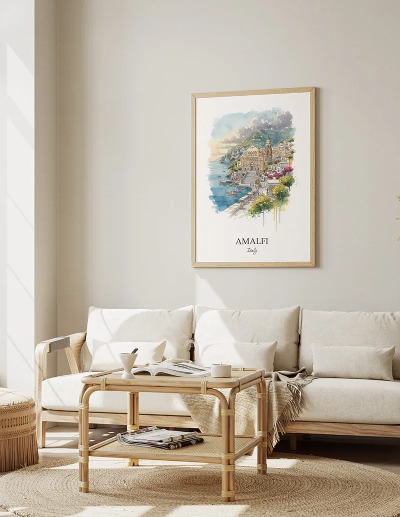 Framed wall art featuring Amalfi, Italy in a light wood frame hanging above a sofa in a modern living room.