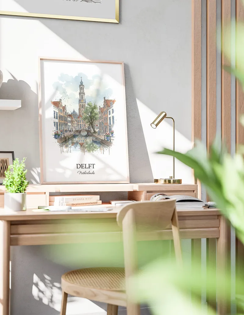 Cozy, well-lit workspace with a minimalist poster of Delft, Netherlands in a light frame sitting on the desk.