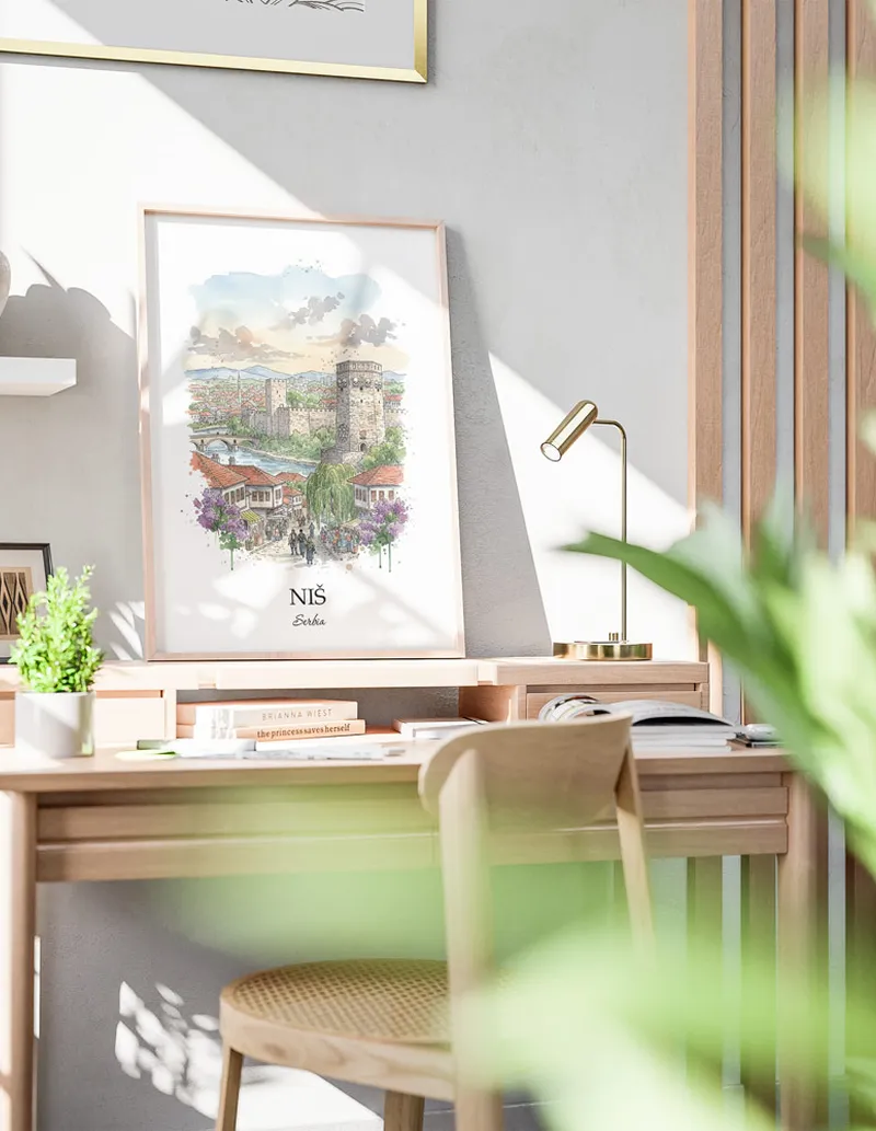 Cozy, well-lit workspace with a minimalist poster of Ni_, Serbia in a light frame sitting on the desk.
