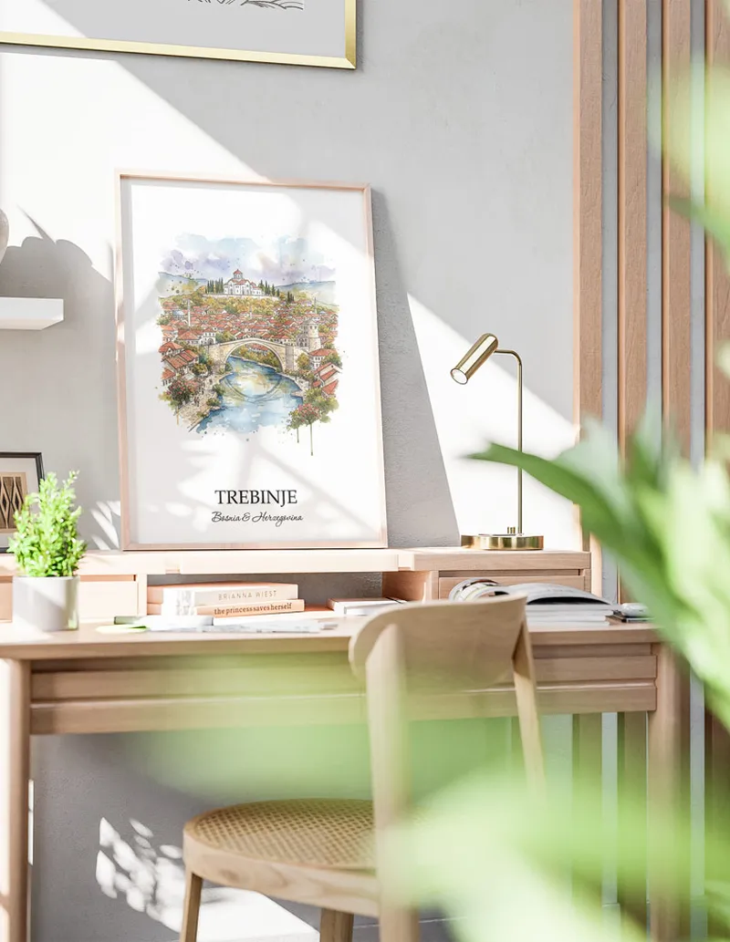 Cozy, well-lit workspace with a minimalist poster of Trebinje, Bosnia & Herzegovina in a light frame sitting on the desk.