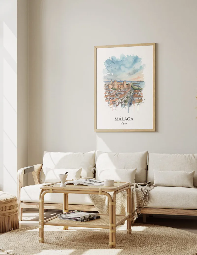 Framed wall art featuring Málaga, Spain in a light wood frame hanging above a sofa in a modern living room.