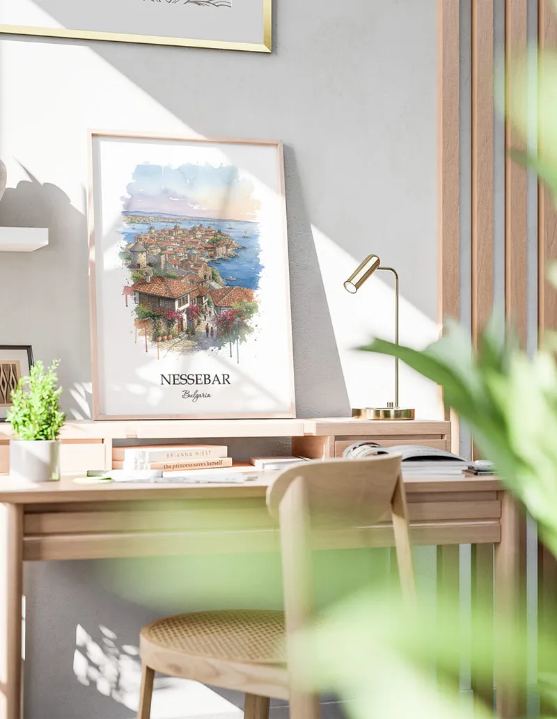 Cozy, well-lit workspace with a minimalist poster of Nessebar, Bulgaria in a light frame sitting on the desk.