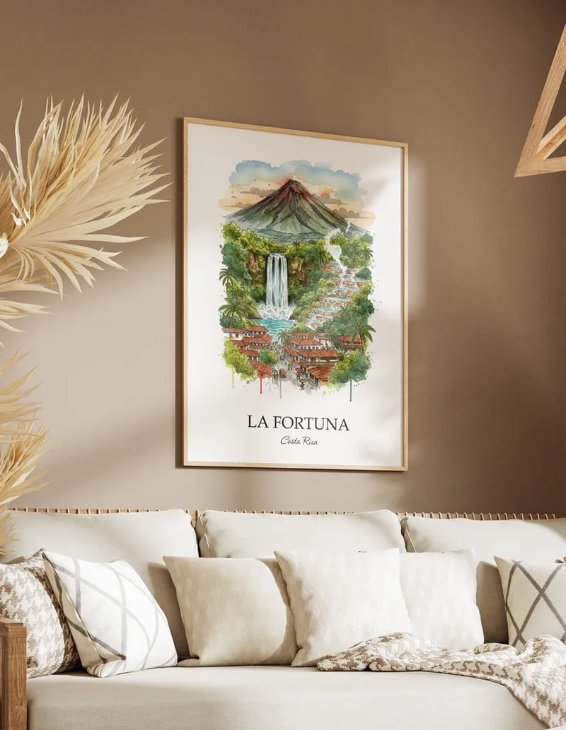 Vintage travel poster of La Fortuna city, Costa Rica in a light frame displayed above a sofa in a bright boho interior.