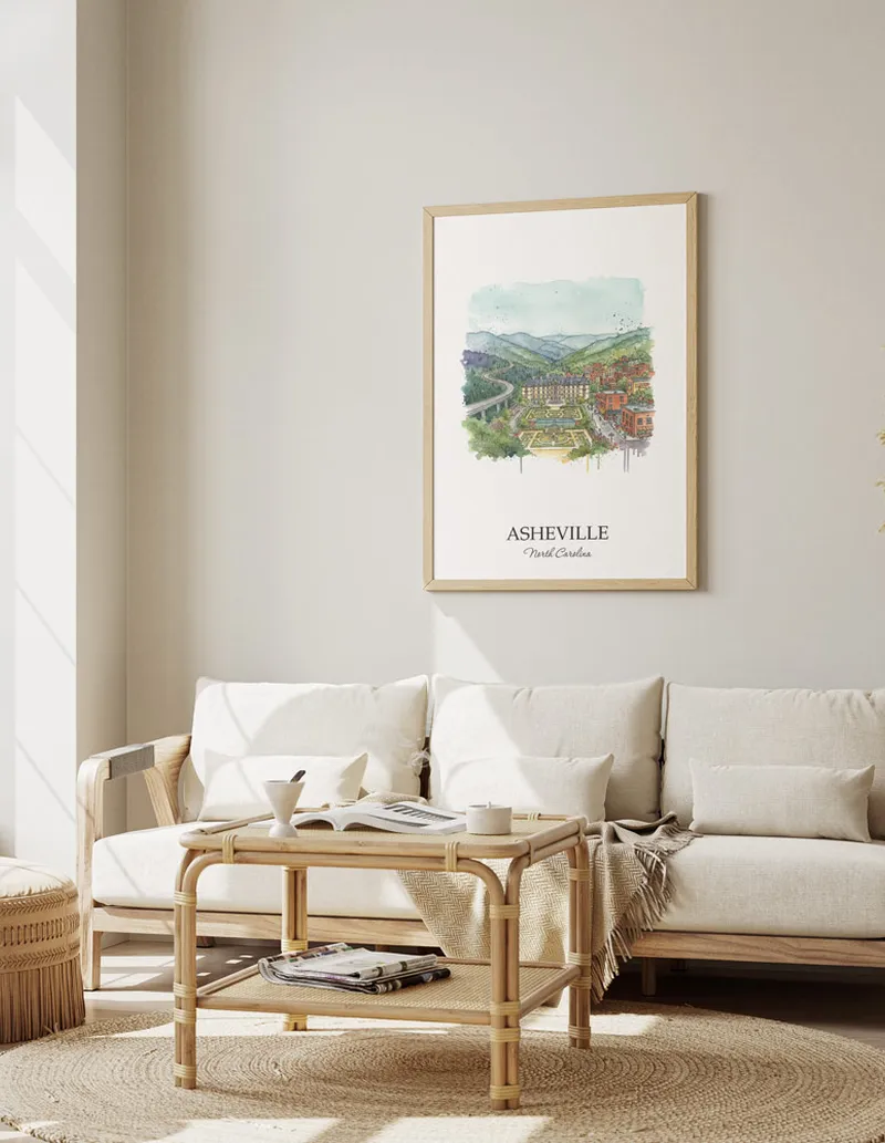Framed wall art featuring Asheville, USA - North Carolina in a light wood frame hanging above a sofa in a modern living room.