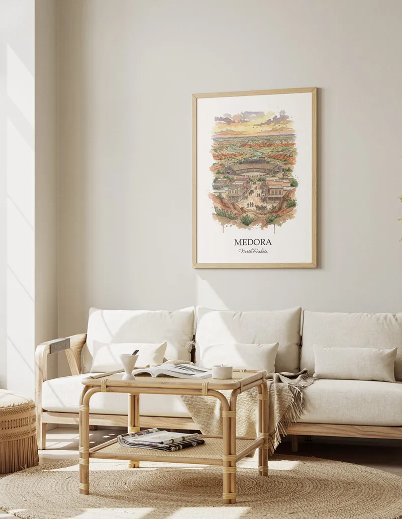 Framed wall art featuring Medora, USA - North Dakota in a light wood frame hanging above a sofa in a modern living room.