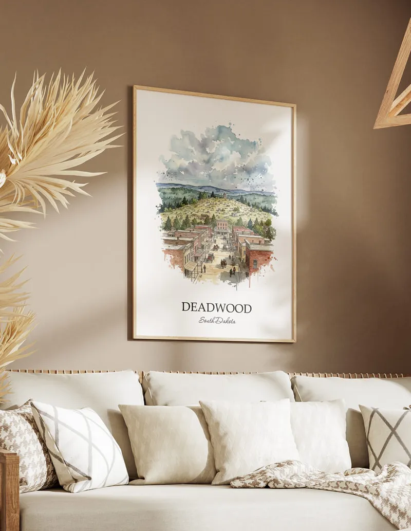 Vintage travel poster of Deadwood city, USA - South Dakota in a light frame displayed above a sofa in a bright boho interior.