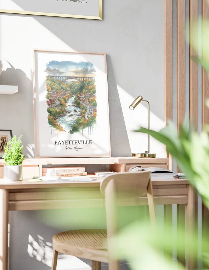 Cozy, well-lit workspace with a minimalist poster of Fayetteville, USA - West Virginia in a light frame sitting on the desk.