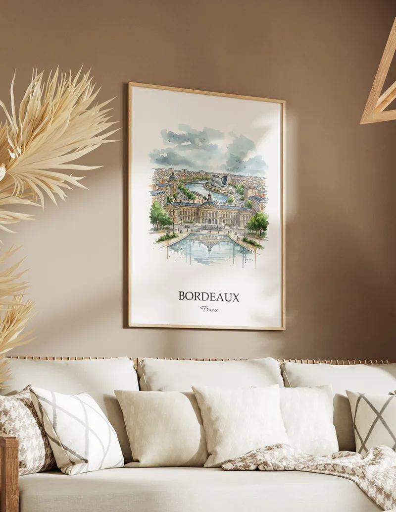 Vintage travel poster of Bordeaux city, France in a light frame displayed above a sofa in a bright boho interior.