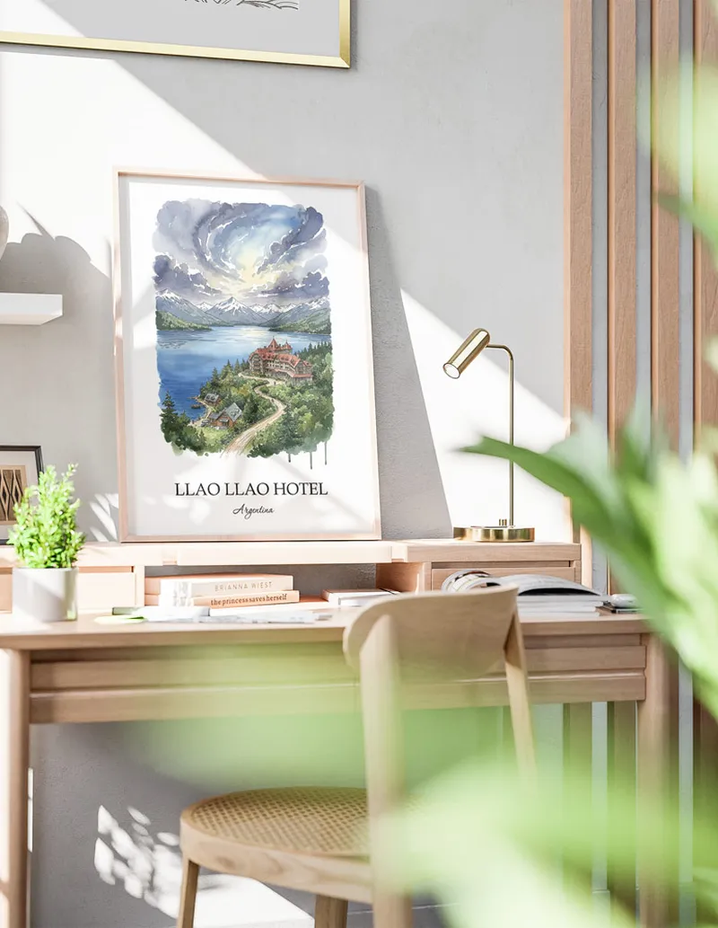 Cozy, well-lit workspace with a minimalist poster of Llao Llao Hotel, Argentina in a light frame sitting on the desk.
