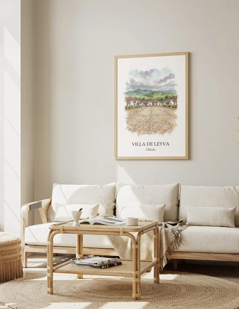 Vintage travel poster of Villa de Leyva, Colombia in a light frame displayed above a sofa in a bright boho interior.