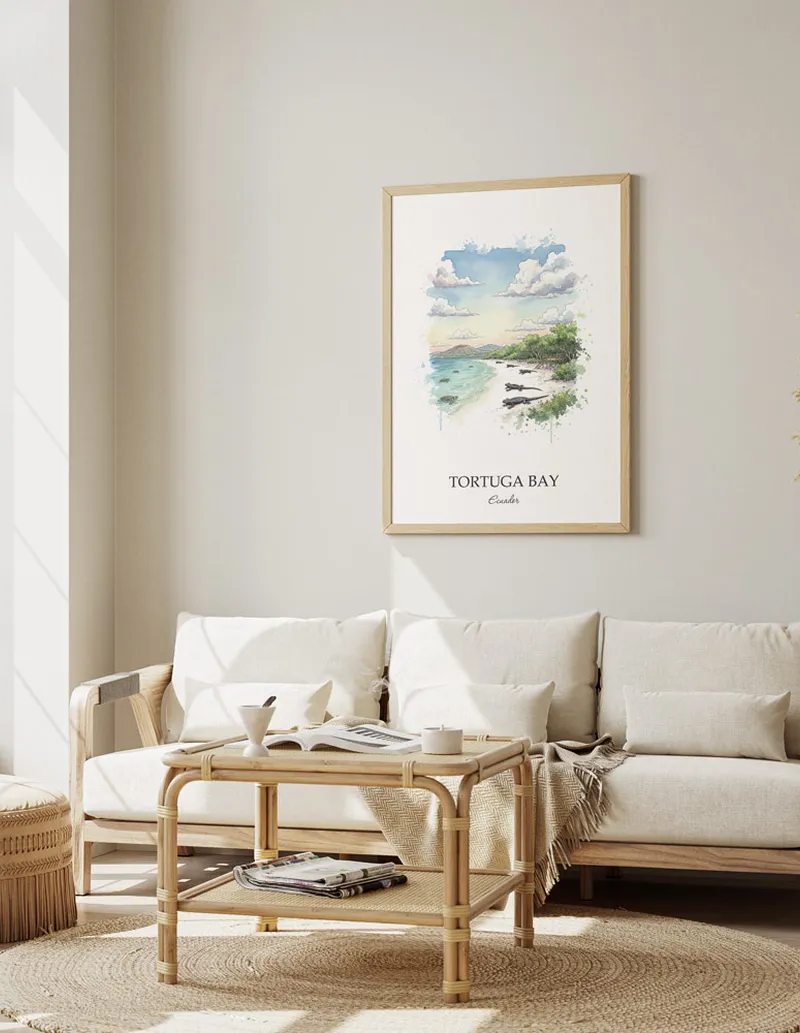 Vintage travel poster of Tortuga Bay, Ecuador in a light frame displayed above a sofa in a bright boho interior.