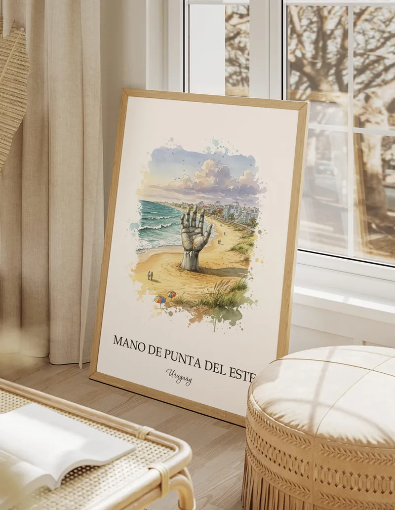 Framed wall art featuring Mano de Punta del Este, Uruguay in a light wood frame hanging above a sofa in a modern living room.