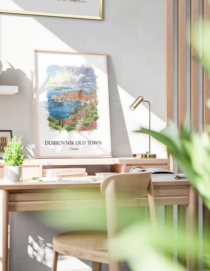 Cozy, well-lit workspace with a minimalist poster of Dubrovnik Old Town, Croatia in a light frame sitting on the desk.