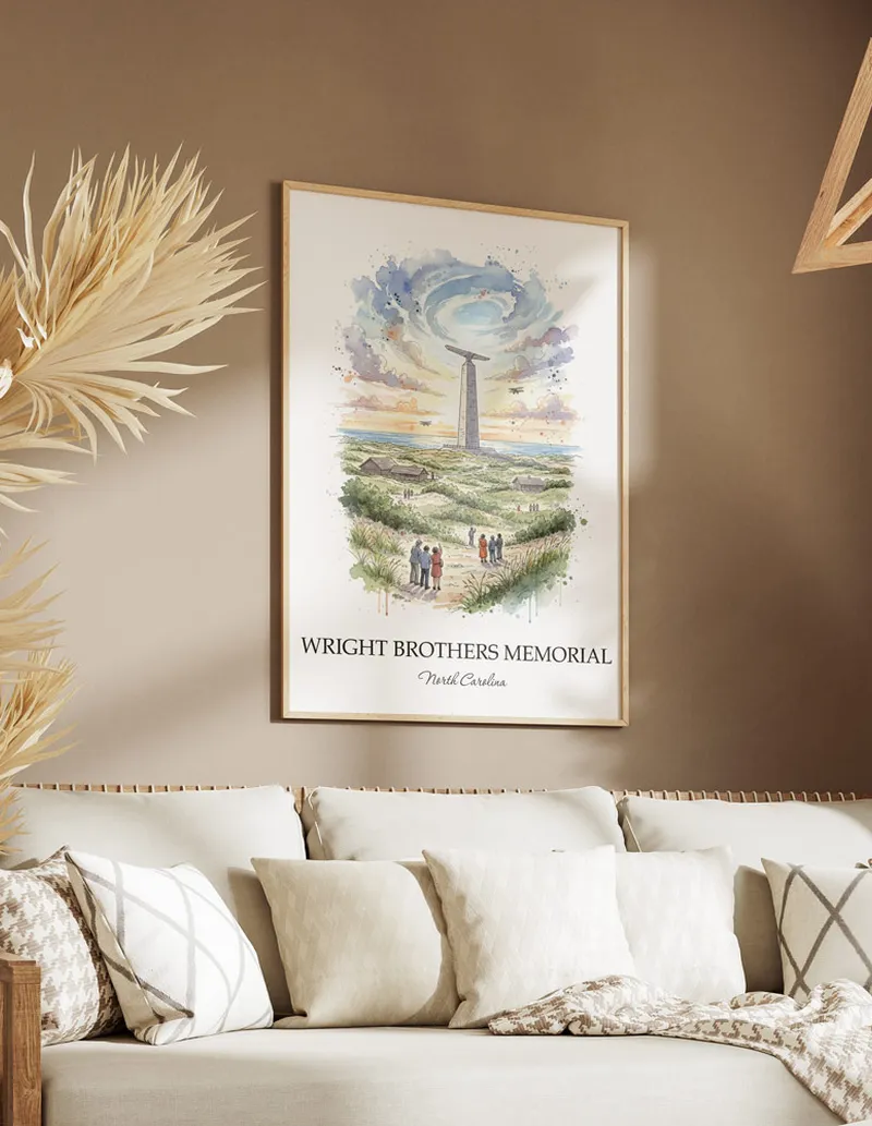Cozy, well-lit workspace with a minimalist poster of Wright Brothers Memorial, North Carolina in a light frame sitting on the desk.