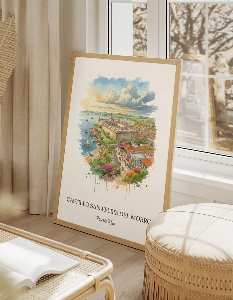 Vintage travel poster of Castillo San Felipe del Morro, Puerto Rico in a light frame displayed above a sofa in a bright boho interior.