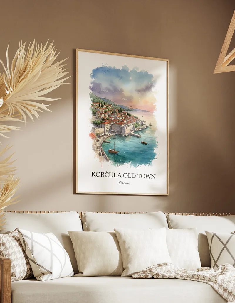 Vintage travel poster of Kor_ula Old Town, Croatia in a light frame displayed above a sofa in a bright boho interior.