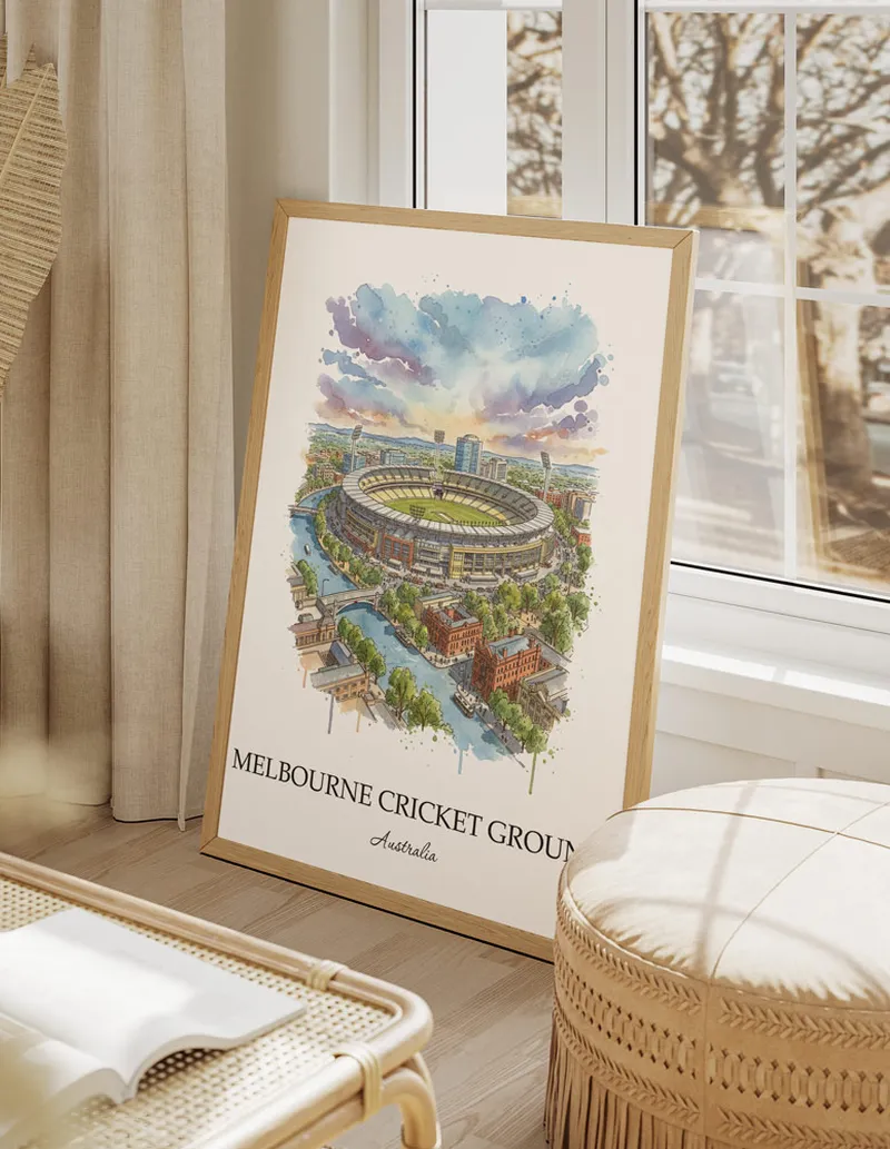 Cozy, well-lit workspace with a minimalist poster of Melbourne Cricket Ground, Australia in a light frame sitting on the desk.