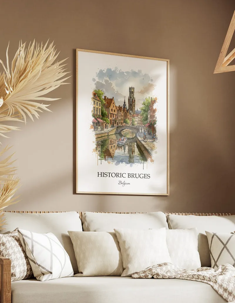 Vintage travel poster of Historic Bruges, Belgium in a light frame displayed above a sofa in a bright boho interior.