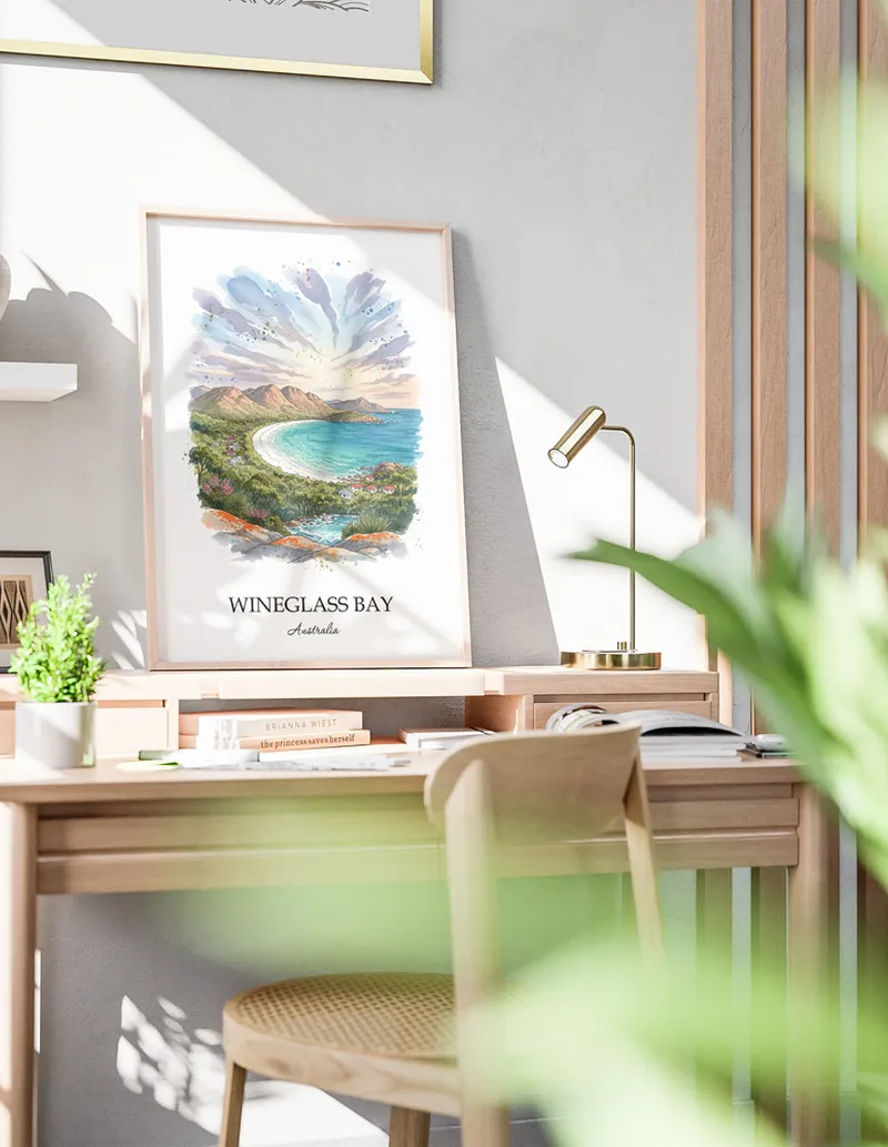 Minimalist poster of Wineglass Bay in Australia in a light frame standing on the floor in a dark moody interior.