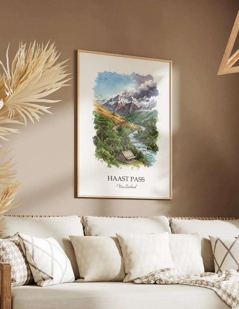 Minimalist poster of Haast Pass in New Zealand in a light frame standing on the floor in a dark moody interior.