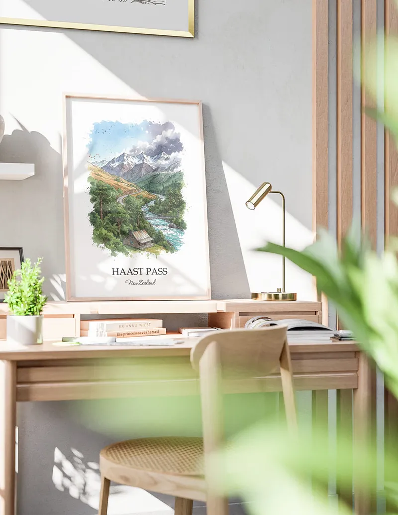 Minimalist poster of Haast Pass in New Zealand in a light frame standing by a window in a boho style room.