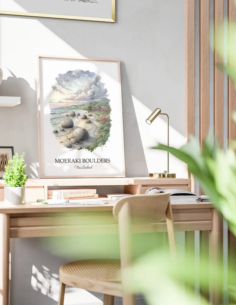 Minimalist poster of Moeraki Boulders in New Zealand in a light frame standing by a window in a boho style room.
