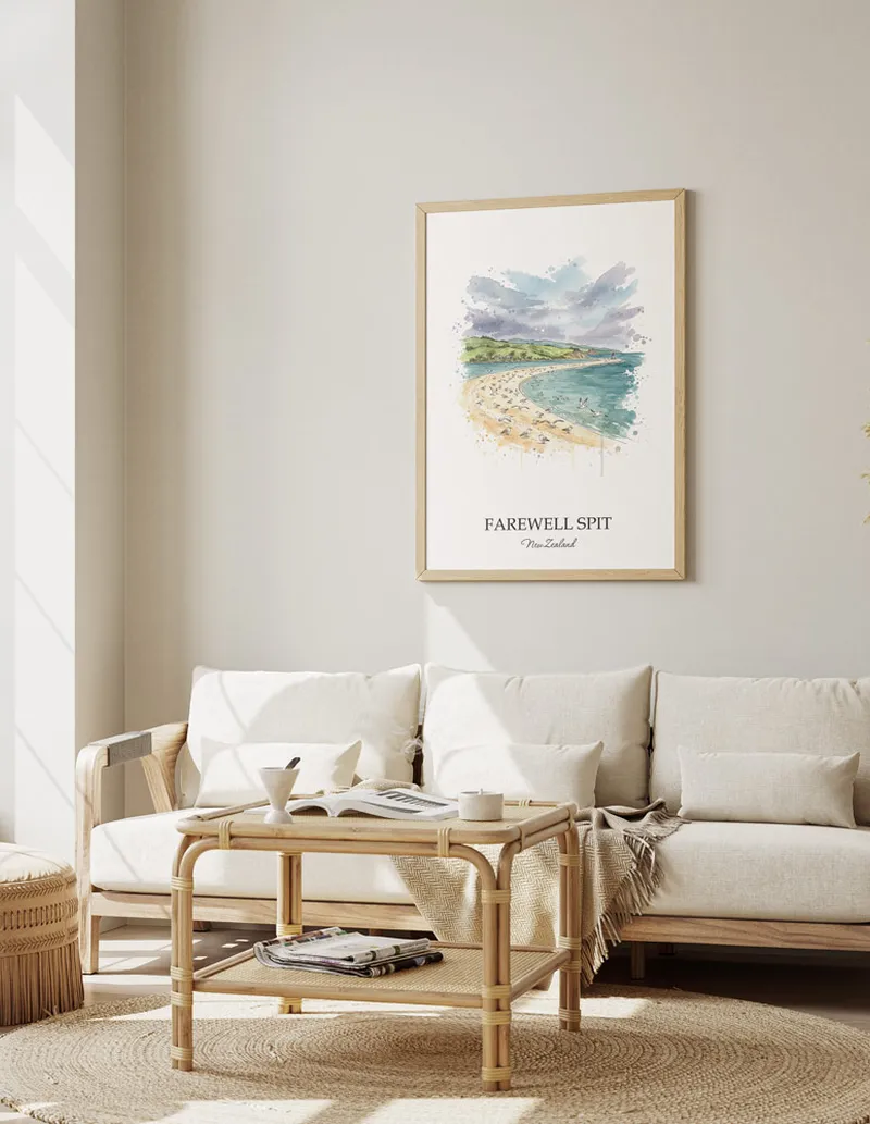 Framed wall art featuring Farewell Spit in New Zealand in a light wood frame leaning on the floor.