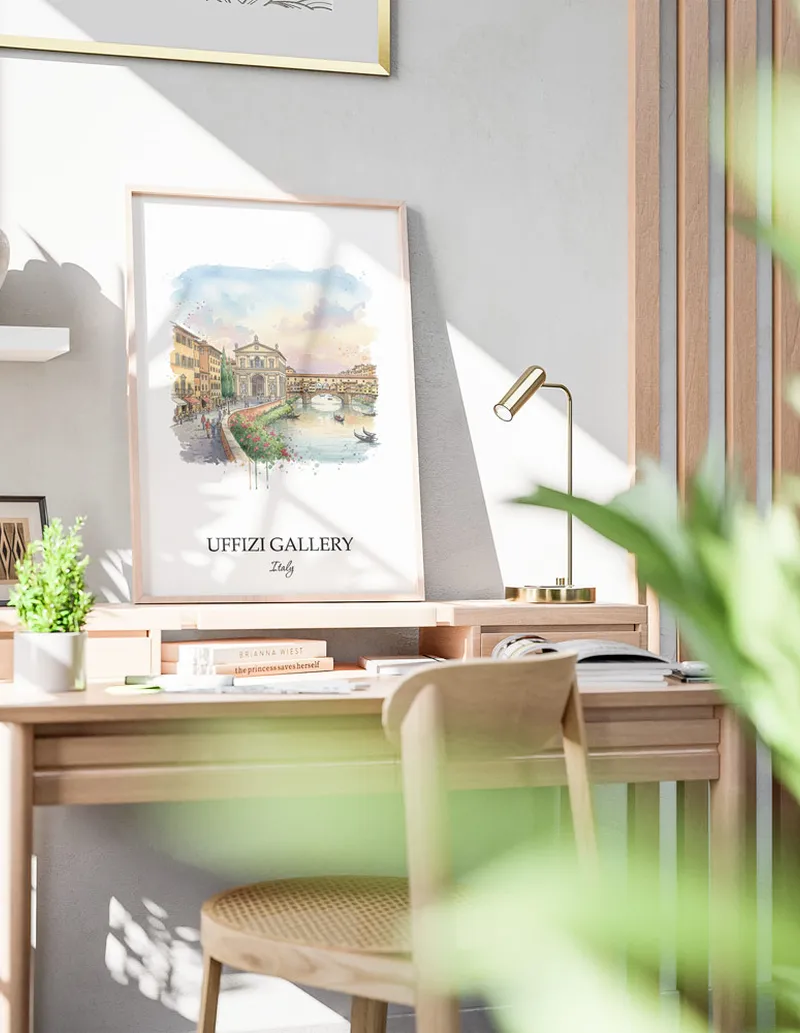 Cozy, well-lit workspace with a minimalist poster of Uffizi Gallery, Italy in a light frame sitting on the desk.
