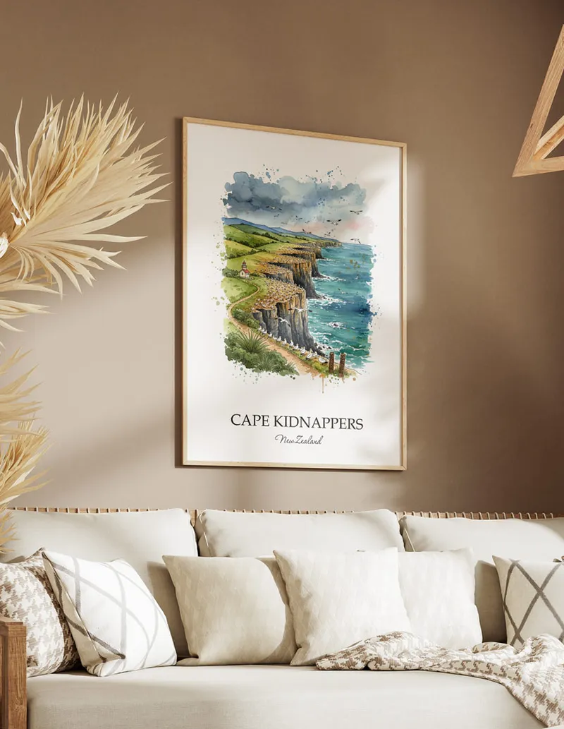 Minimalist poster of Cape Kidnappers in New Zealand in a light frame standing on the floor in a dark moody interior.