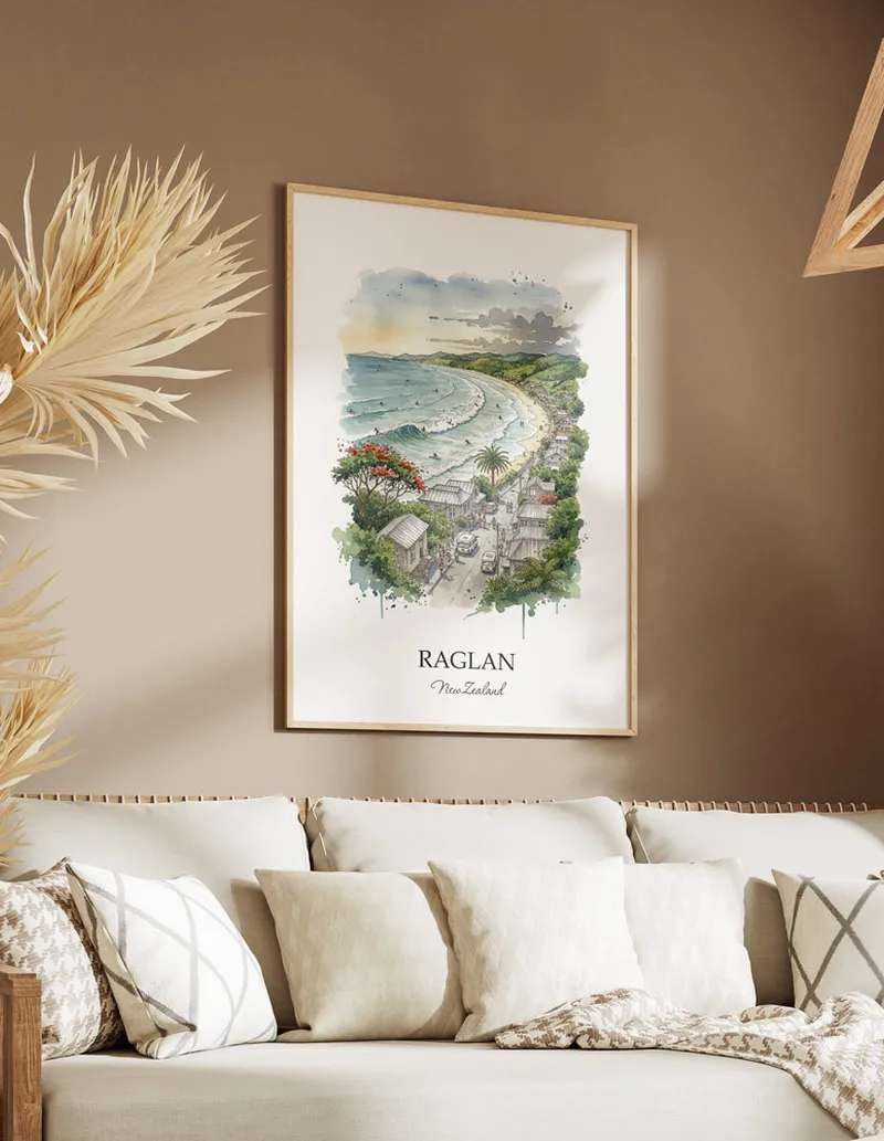 Minimalist poster of Raglan in New Zealand in a light frame standing on the floor in a dark moody interior.