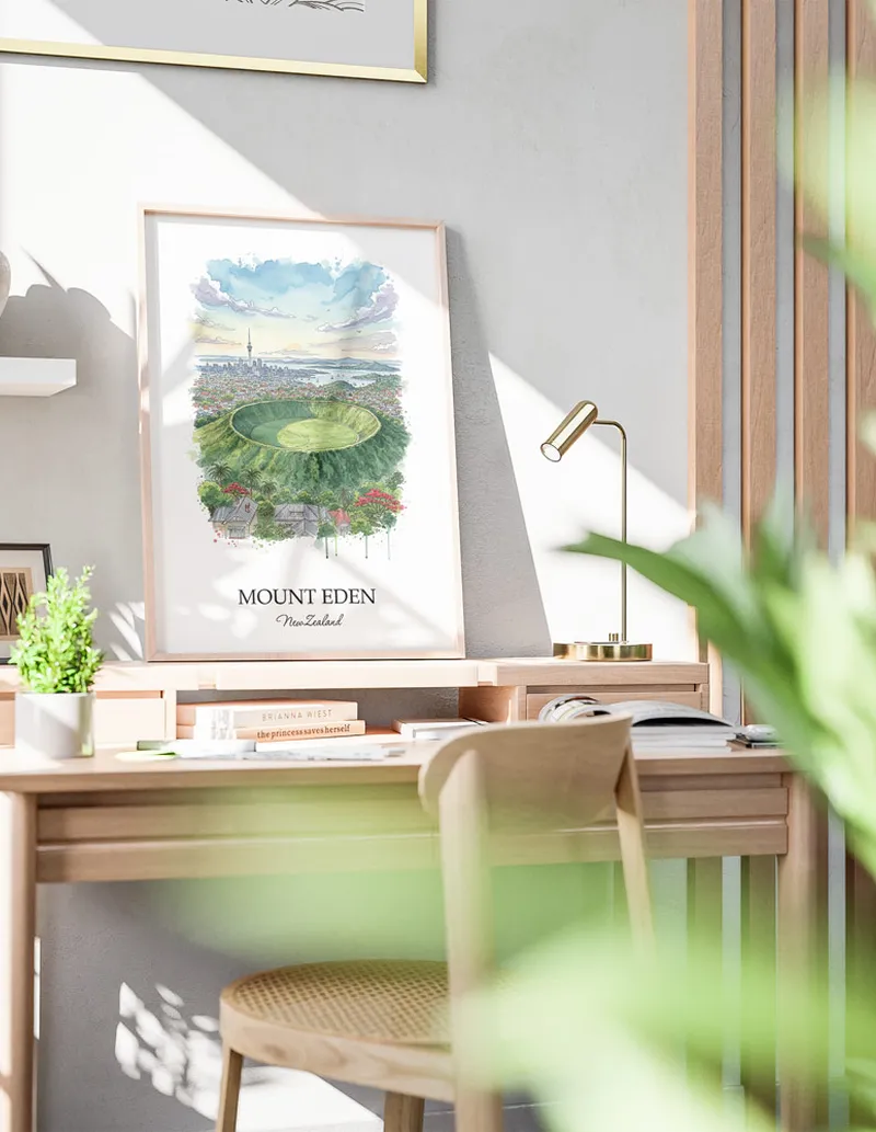 Minimalist poster of Mount Eden in New Zealand in a light frame standing by a window in a boho style room.