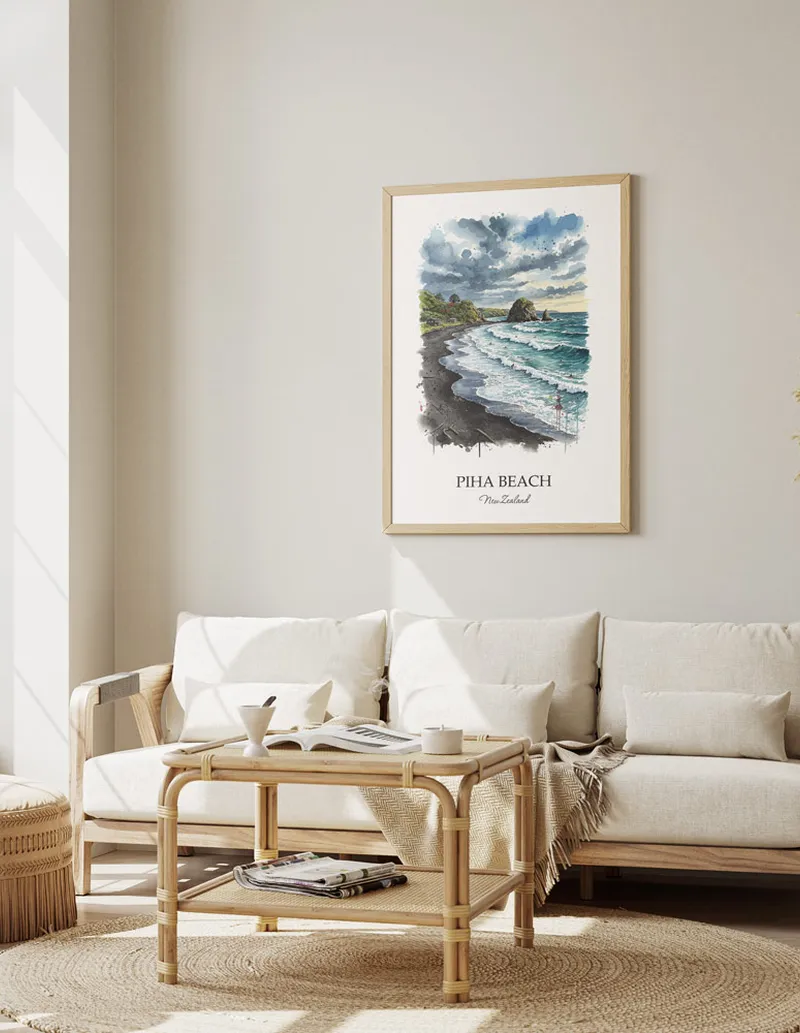 Framed wall art featuring Piha Beach in New Zealand in a light wood frame leaning on the floor.