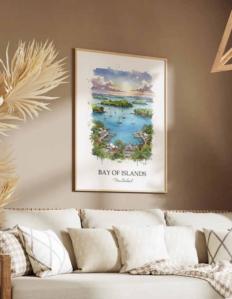 Minimalist poster of Bay of Islands in New Zealand in a light frame standing on the floor in a dark moody interior.