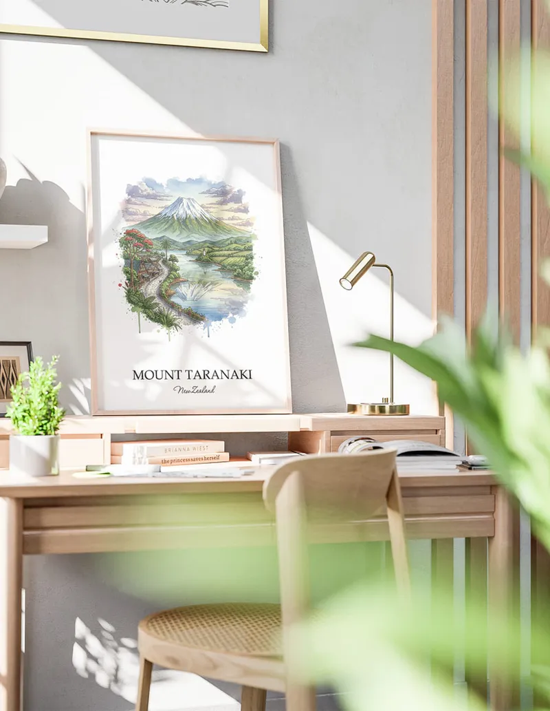 Minimalist poster of Mount Taranaki in New Zealand in a light frame standing by a window in a boho style room.