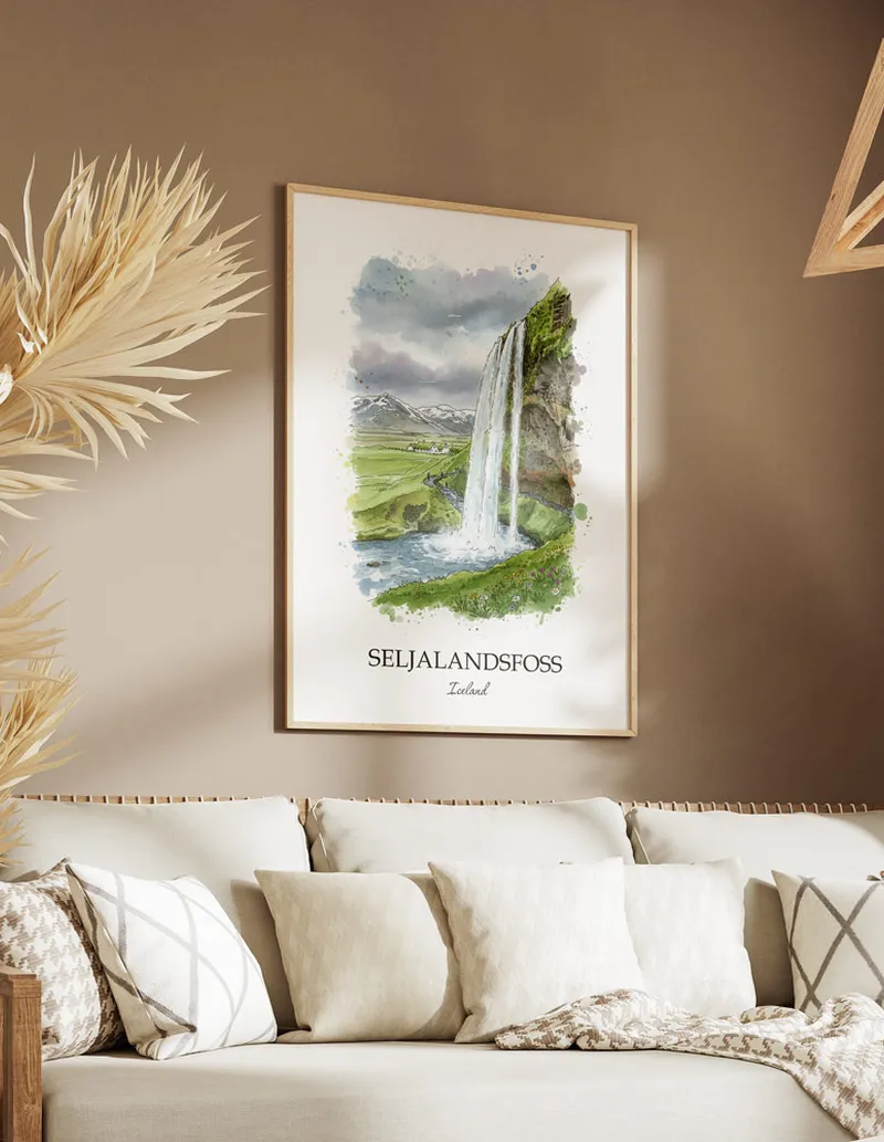 Vintage travel poster of Seljalandsfoss, Iceland in a light frame displayed above a sofa in a bright boho interior.