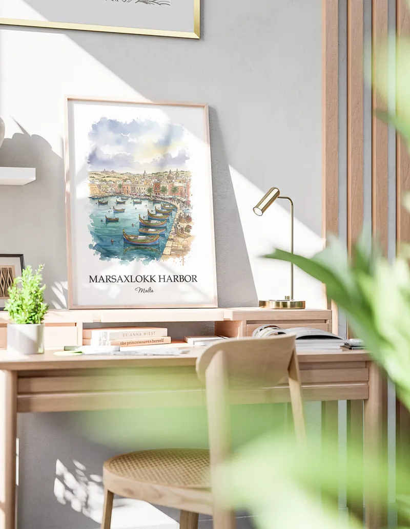 Cozy, well-lit workspace with a minimalist poster of Marsaxlokk Harbor, Malta in a light frame sitting on the desk.