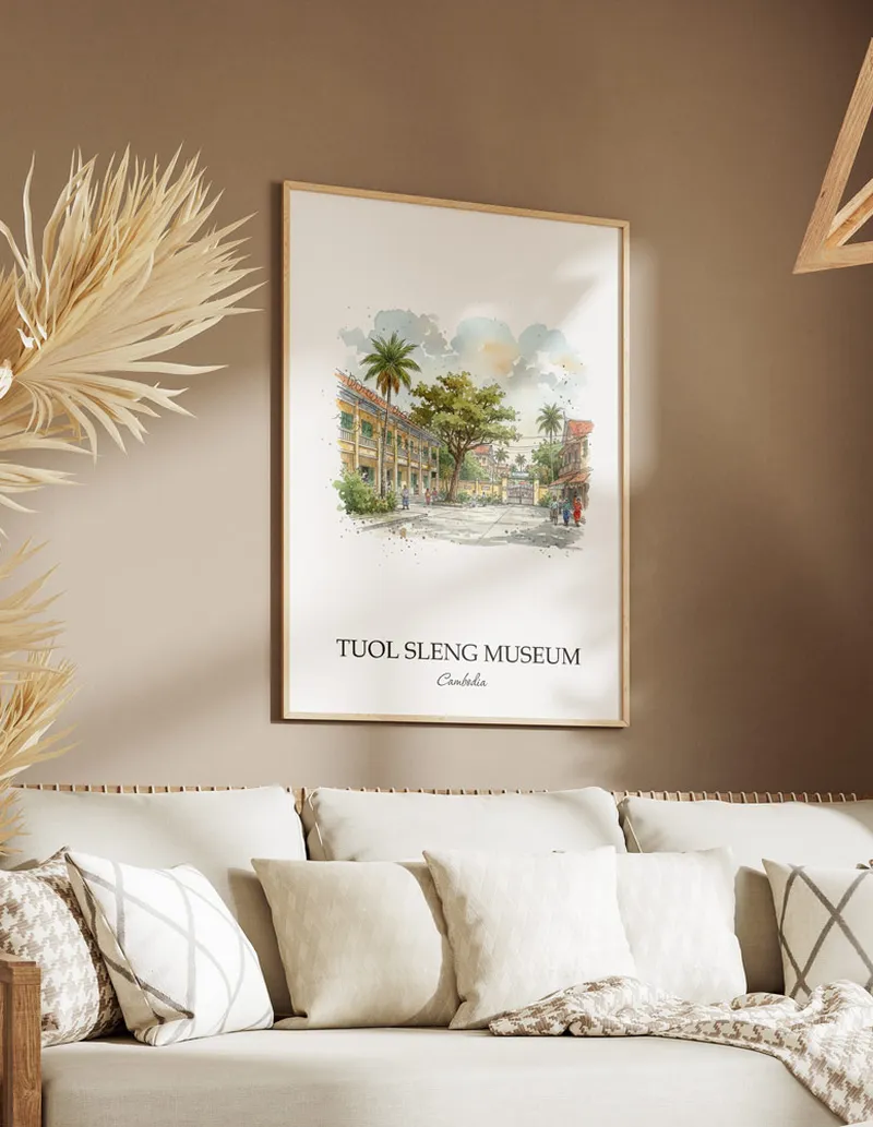 Vintage travel poster of Tuol Sleng Museum, Cambodia in a light frame displayed above a sofa in a bright boho interior.