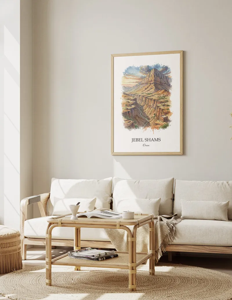 Vintage travel poster of Jebel Shams, Oman in a light frame displayed above a sofa in a bright boho interior.