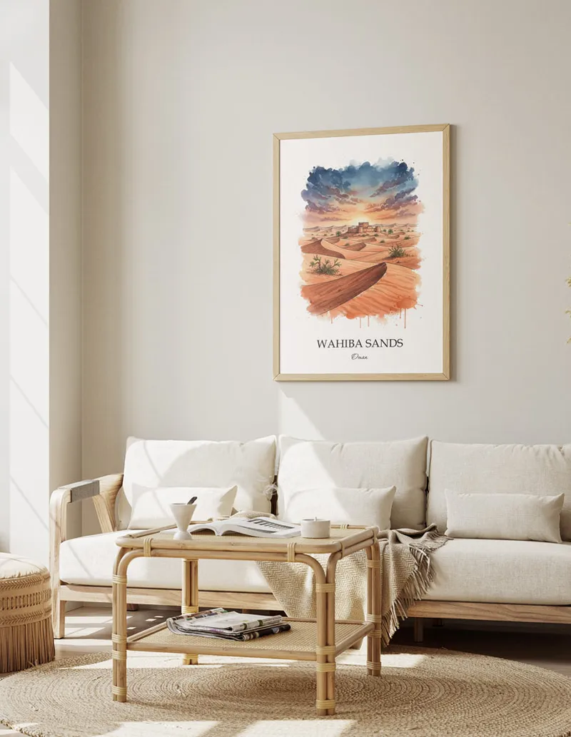 Vintage travel poster of Wahiba Sands, Oman in a light frame displayed above a sofa in a bright boho interior.