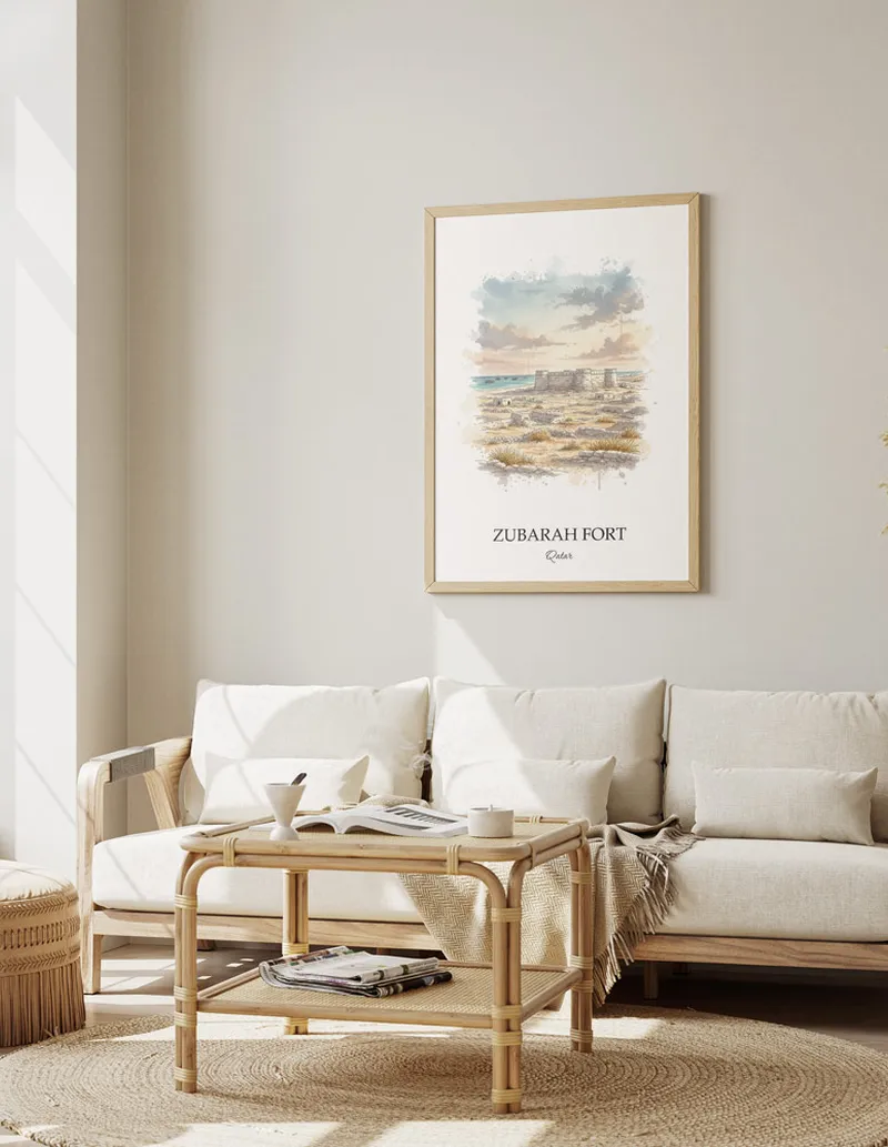 Vintage travel poster of Zubarah Fort, Qatar in a light frame displayed above a sofa in a bright boho interior.