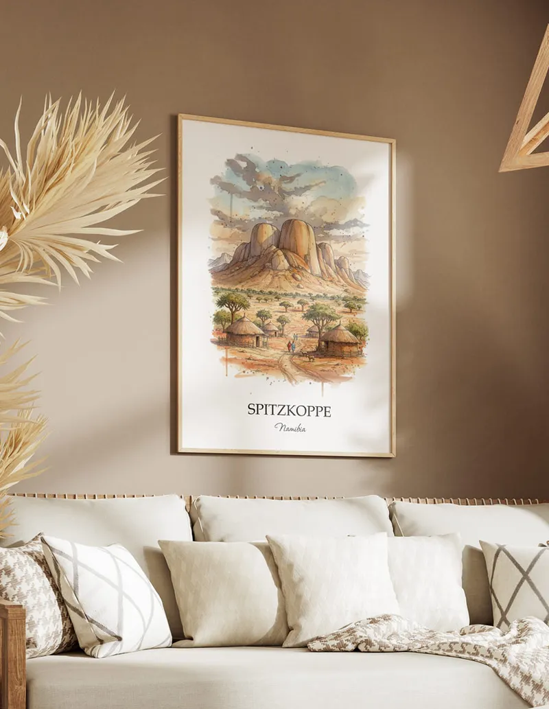 Cozy, well-lit workspace with a minimalist poster of Spitzkoppe, Namibia in a light frame sitting on the desk.
