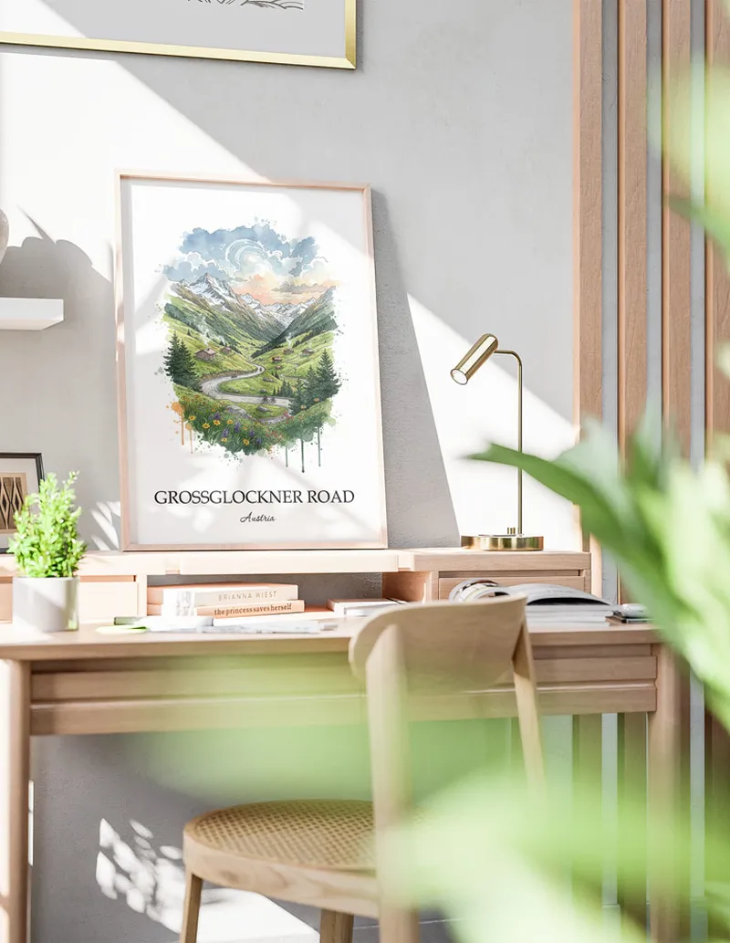 Cozy, well-lit workspace with a minimalist poster of Grossglockner Road, Austria in a light frame sitting on the desk.