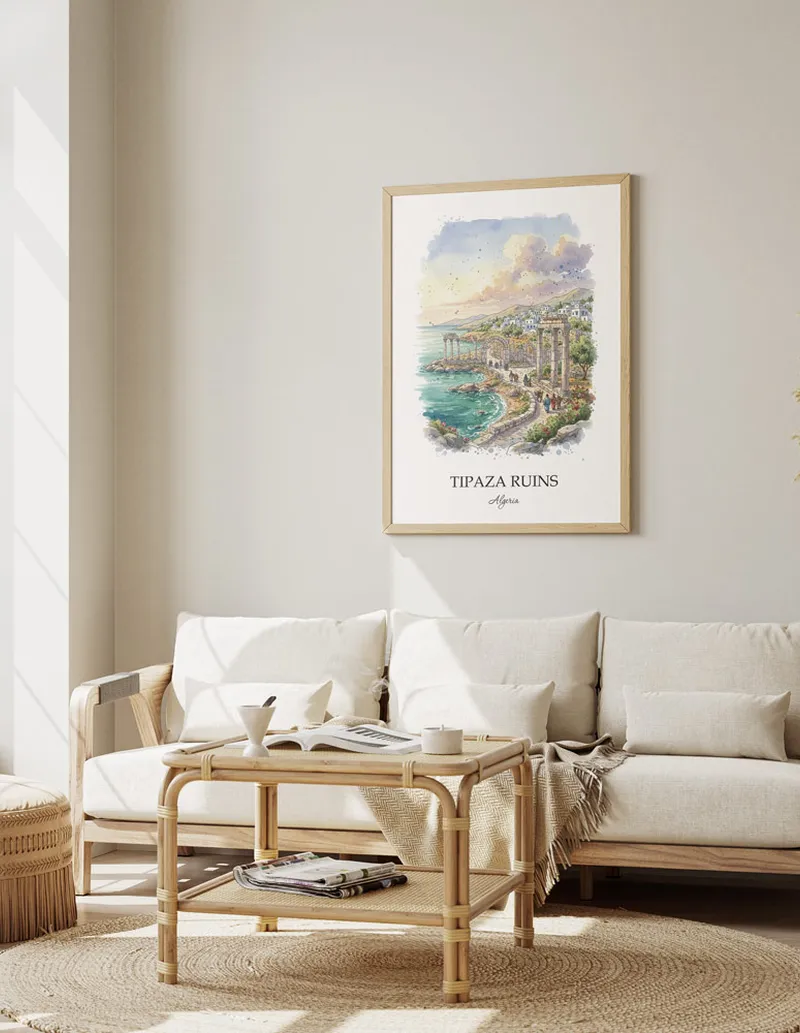 Vintage travel poster of Tipaza Ruins, Algeria in a light frame displayed above a sofa in a bright boho interior.