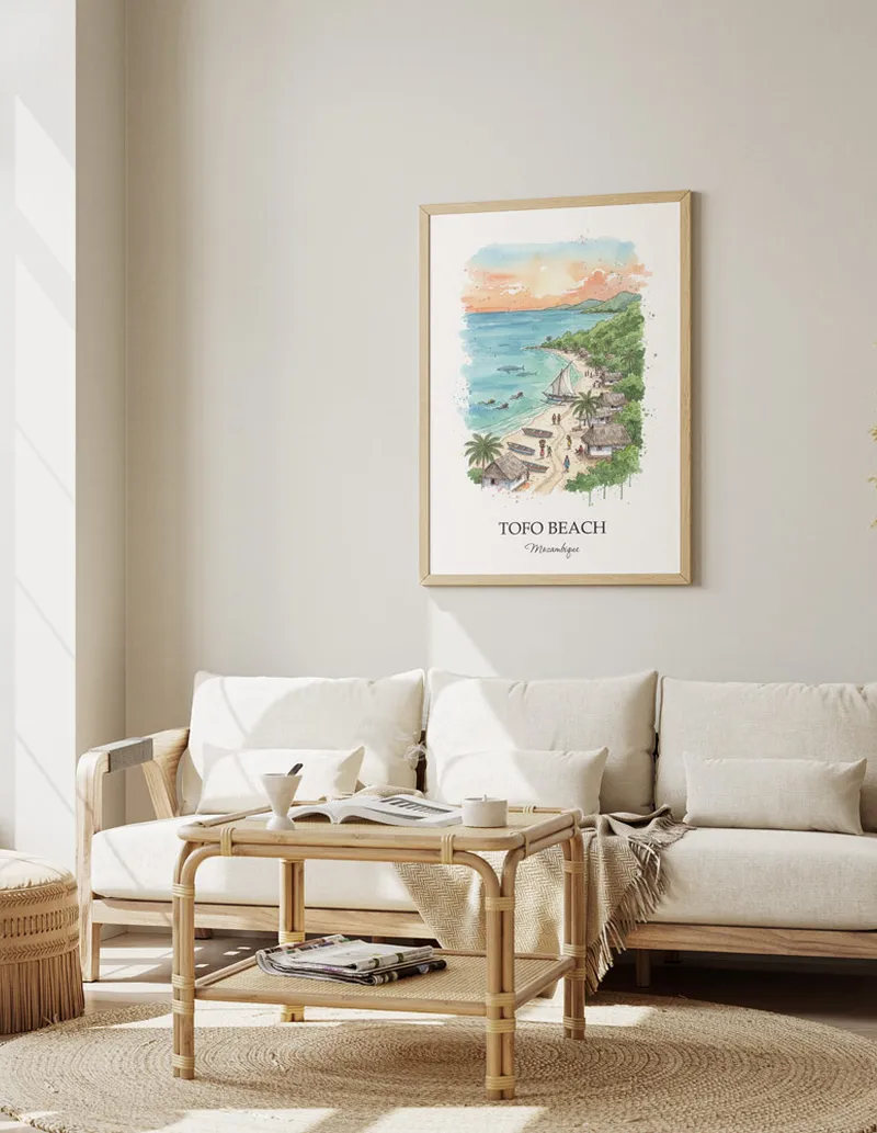 Vintage travel poster of Tofo Beach, Mozambique in a light frame displayed above a sofa in a bright boho interior.