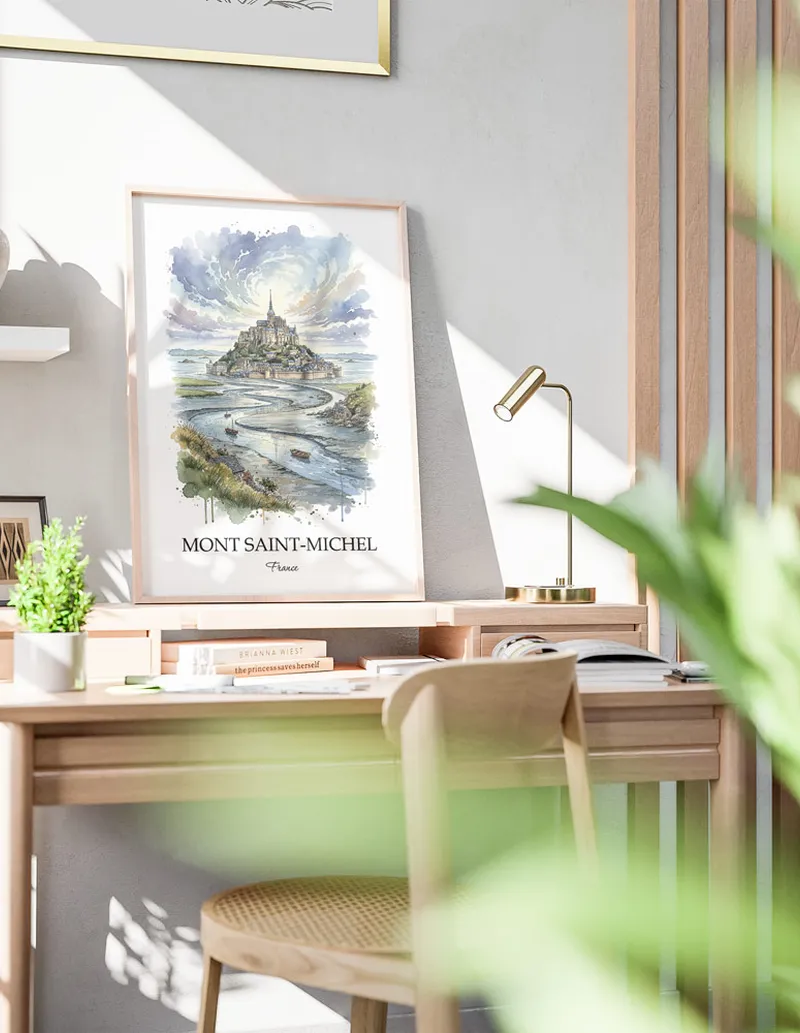 Cozy, well-lit workspace with a minimalist poster of Mont Saint-Michel, France in a light frame sitting on the desk.
