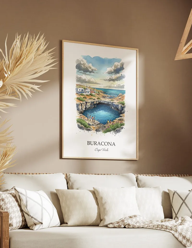 Cozy, well-lit workspace with a minimalist poster of Buracona, Cape Verde in a light frame sitting on the desk.